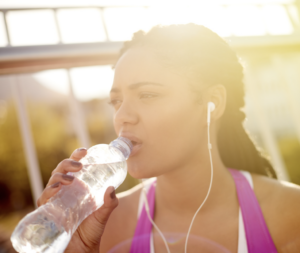 Woman in exercise clothes drinking a bottle of water